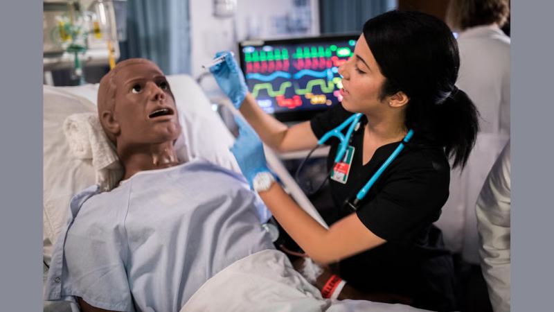 Amanda Leyva ’18 checks the status of Raj Patel, a manikin simulating a patient from a long-term care facility who has experienced complicates from a feeding tube. (Photo by Steven Diaz ’19)